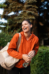 Happy, active woman outdoors with a water bottle and gym bag. Sign up for the uresta newsletter for tips on bladder leak solutions and staying active.